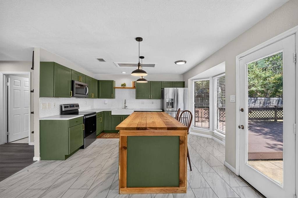 519 Fox Creek Court, Denton, TX 76209 Kitchen featuring green cabinetry, white countertops, tile flooring, a wood-finish island, and a glass-paneled door opening to a deck