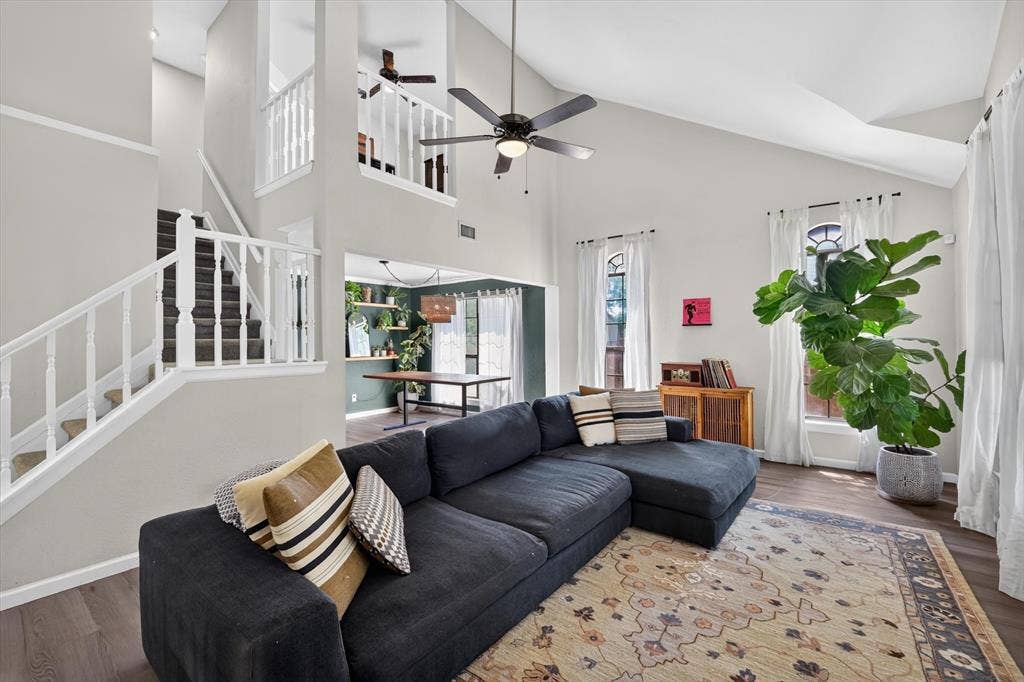 519 Fox Creek Court, Denton, TX 76209 Vaulted ceiling with a ceiling fan, wood-finish flooring, staircase with white balusters, and a second-story landing with a white baluster railing