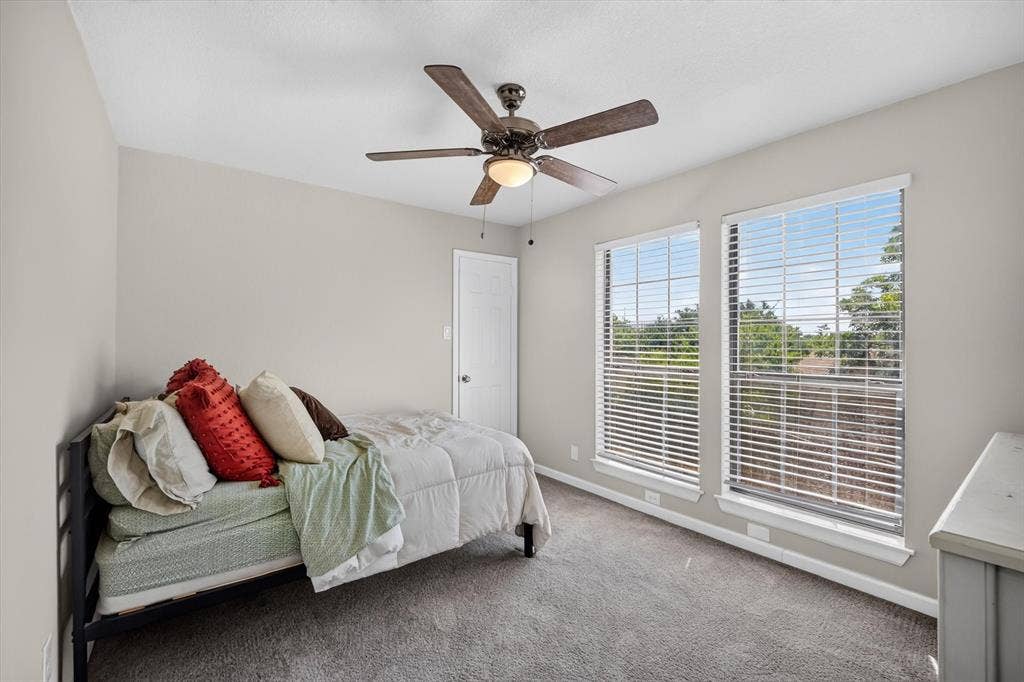 519 Fox Creek Court, Denton, TX 76209 Carpeted room with a ceiling fan, two windows with blinds, and white trim