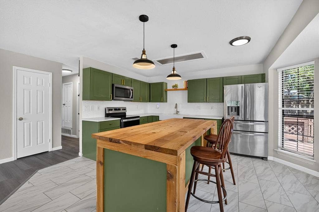 519 Fox Creek Court, Denton, TX 76209 Kitchen featuring green cabinetry, stainless steel appliances, white countertops, and a wood-finish island