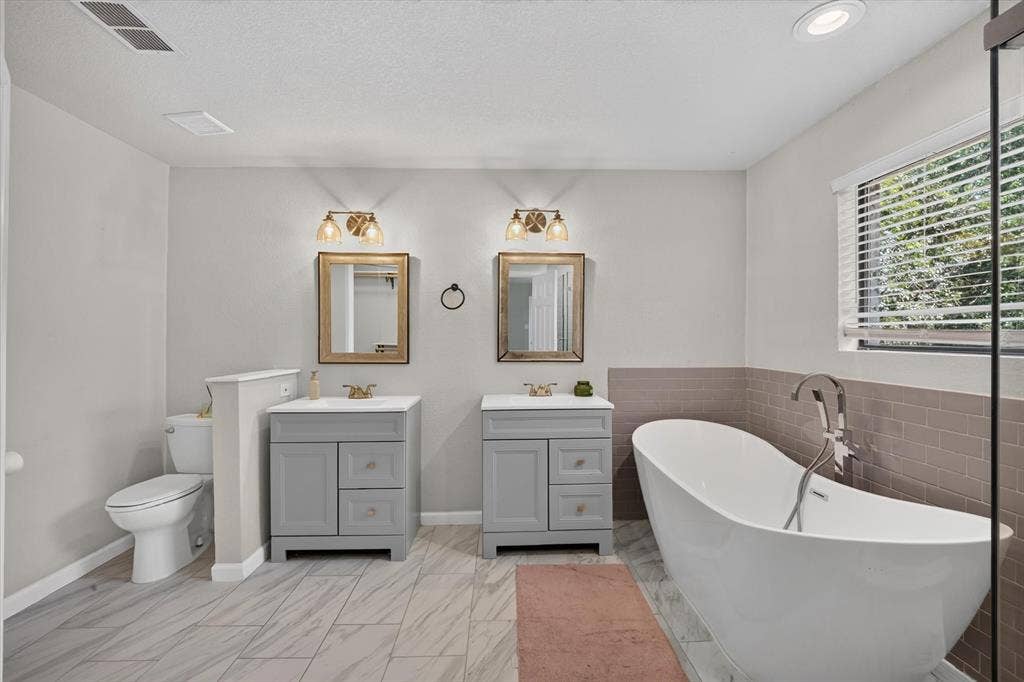 519 Fox Creek Court, Denton, TX 76209 Dual vanity sinks, freestanding soaking tub, tiled flooring, horizontal window blinds, and recessed lighting