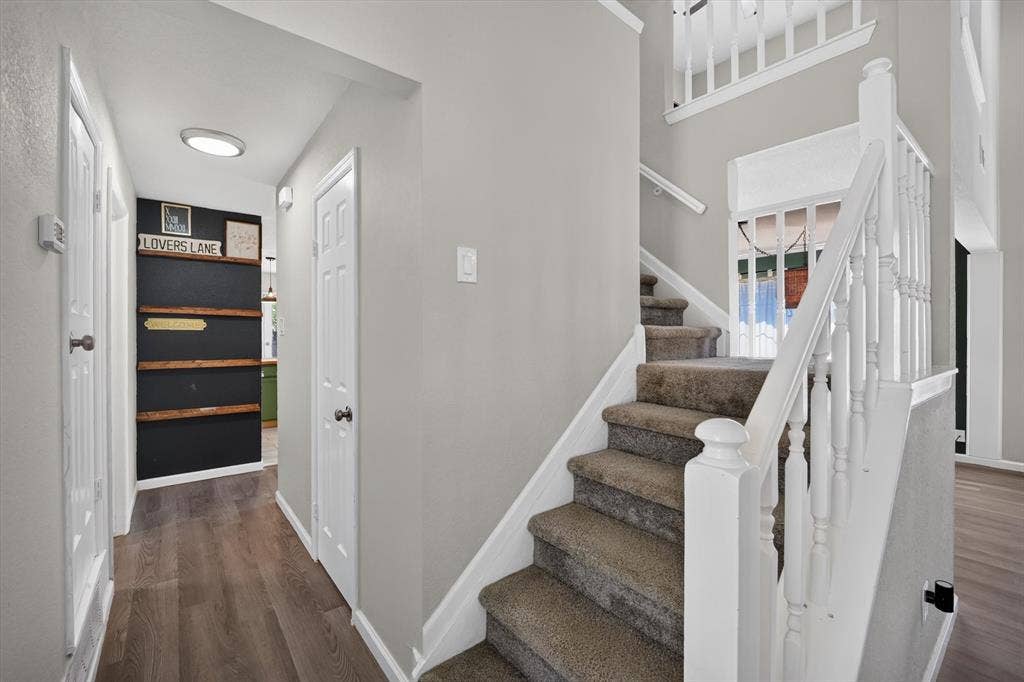 519 Fox Creek Court, Denton, TX 76209 Wood-finish flooring, neutral wall tones, carpeted staircase, white newel posts, and balusters