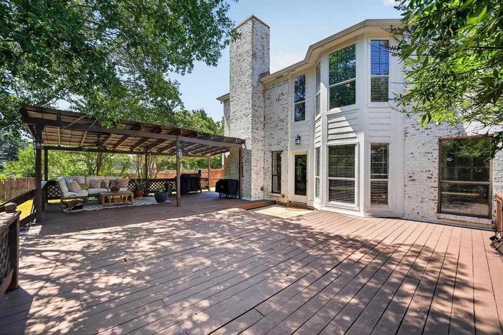 519 Fox Creek Court, Denton, TX 76209 Expansive wood-finish deck with a built-in pergola, offering direct access to the interior through a glass-paneled door