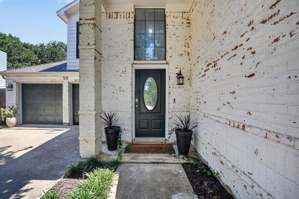 519 Fox Creek Court, Denton, TX 76209 Lime wash brick exterior, covered front entry, dark paneled front door with oval glass insert, transom window, and attached lantern-style light fixture
