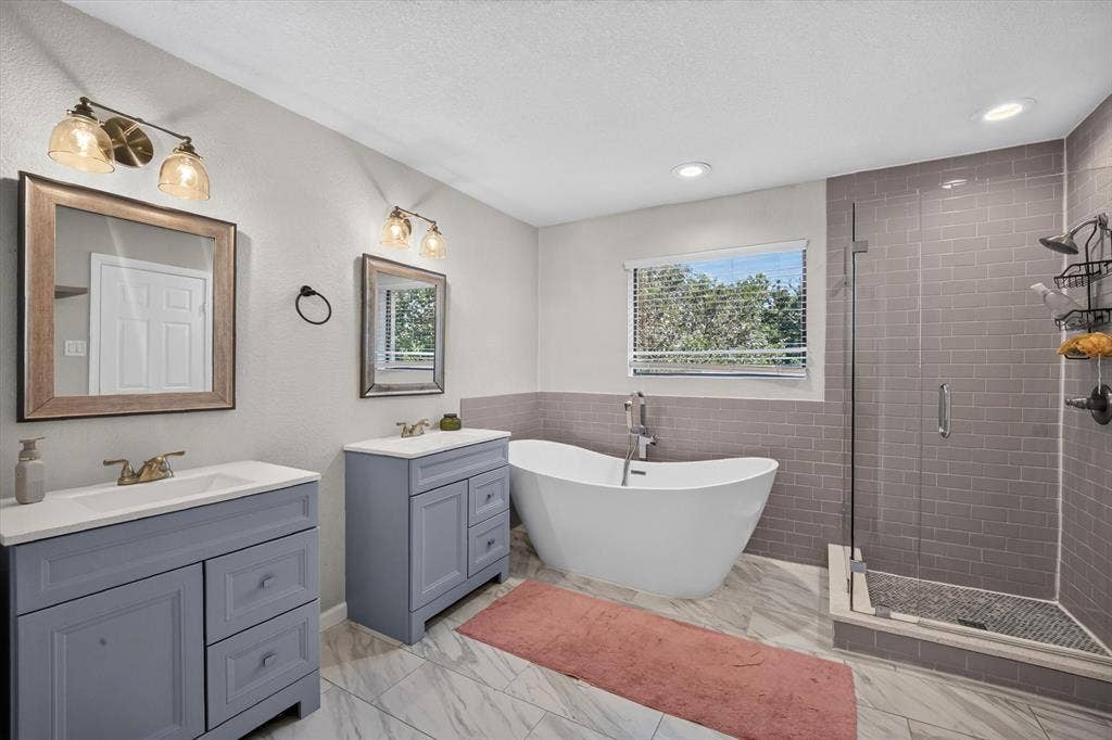 519 Fox Creek Court, Denton, TX 76209 Dual vanities, freestanding soaking tub, glass-enclosed shower with subway tile surround, recessed lighting, and wood-finish flooring