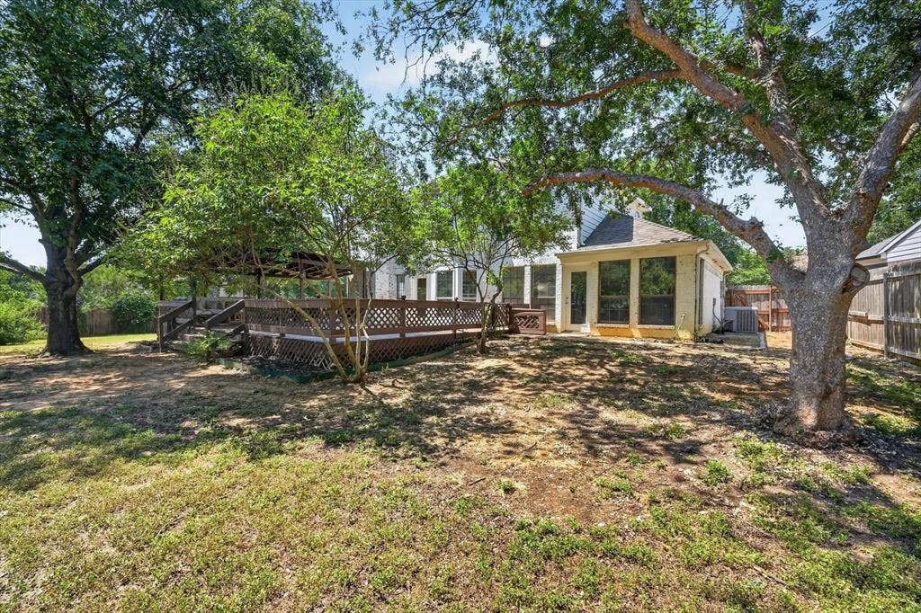 519 Fox Creek Court, Denton, TX 76209 Expansive backyard featuring a multi-level wood deck, mature trees, and a screened-in porch