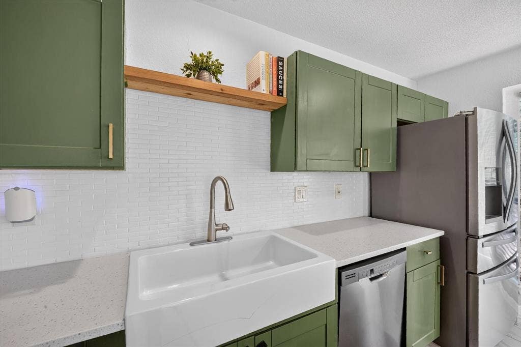 519 Fox Creek Court, Denton, TX 76209 Kitchen featuring green cabinetry, white subway tile backsplash, white farmhouse sink, and light-toned countertops