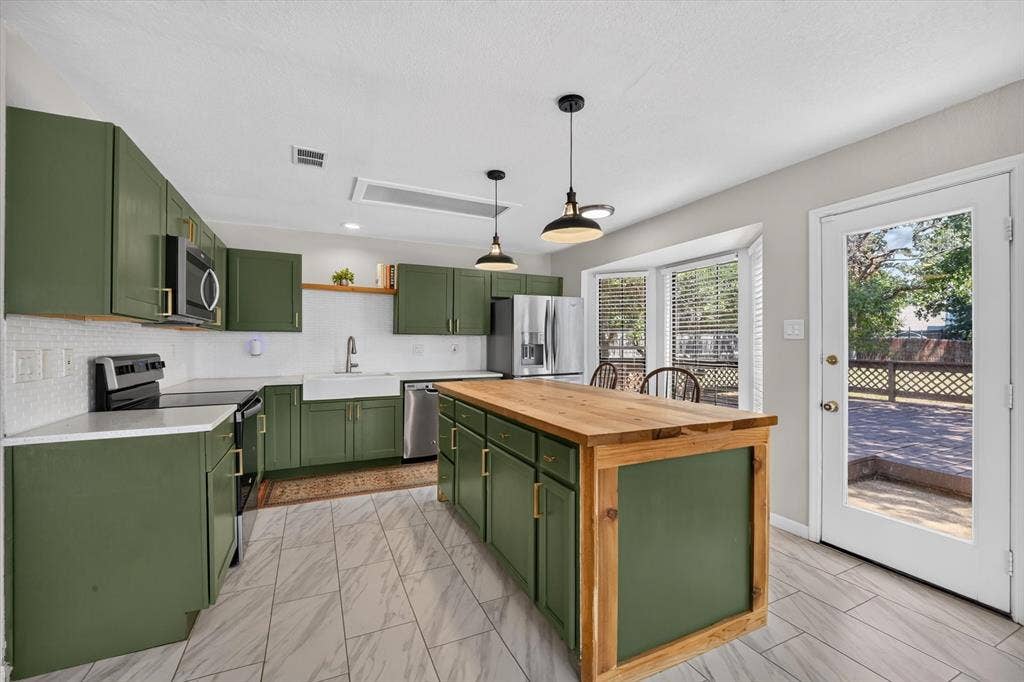 519 Fox Creek Court, Denton, TX 76209 Kitchen featuring green cabinetry, wood-finish island countertop, stainless steel appliances, and white tile flooring
