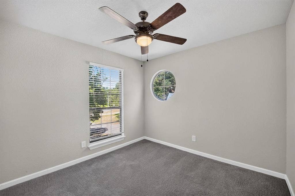 519 Fox Creek Court, Denton, TX 76209 Carpeted room featuring a ceiling fan with light, rectangular window with blinds, and a circular window