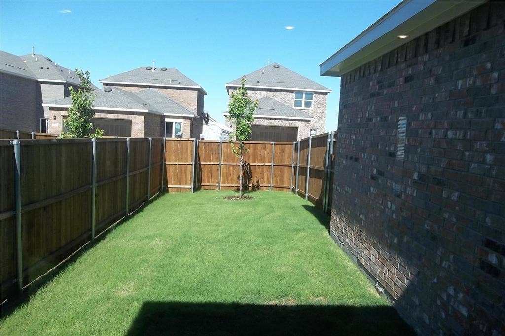 3208 Dillonwood Street, Celina, TX 75009 Enclosed backyard featuring a manicured lawn, established privacy fencing, and brick exterior