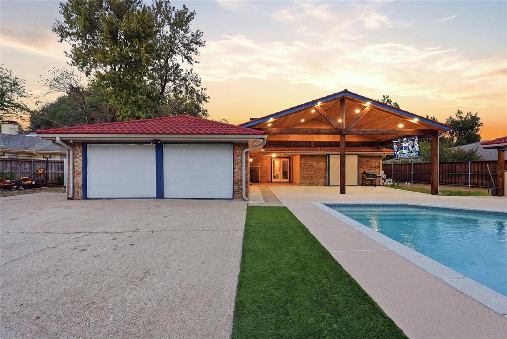 1010 Florence Drive, Duncanville, TX 75116 Expansive concrete driveway, two-car garage with red tile roofing, inground swimming pool, and a covered patio with exposed wood beams