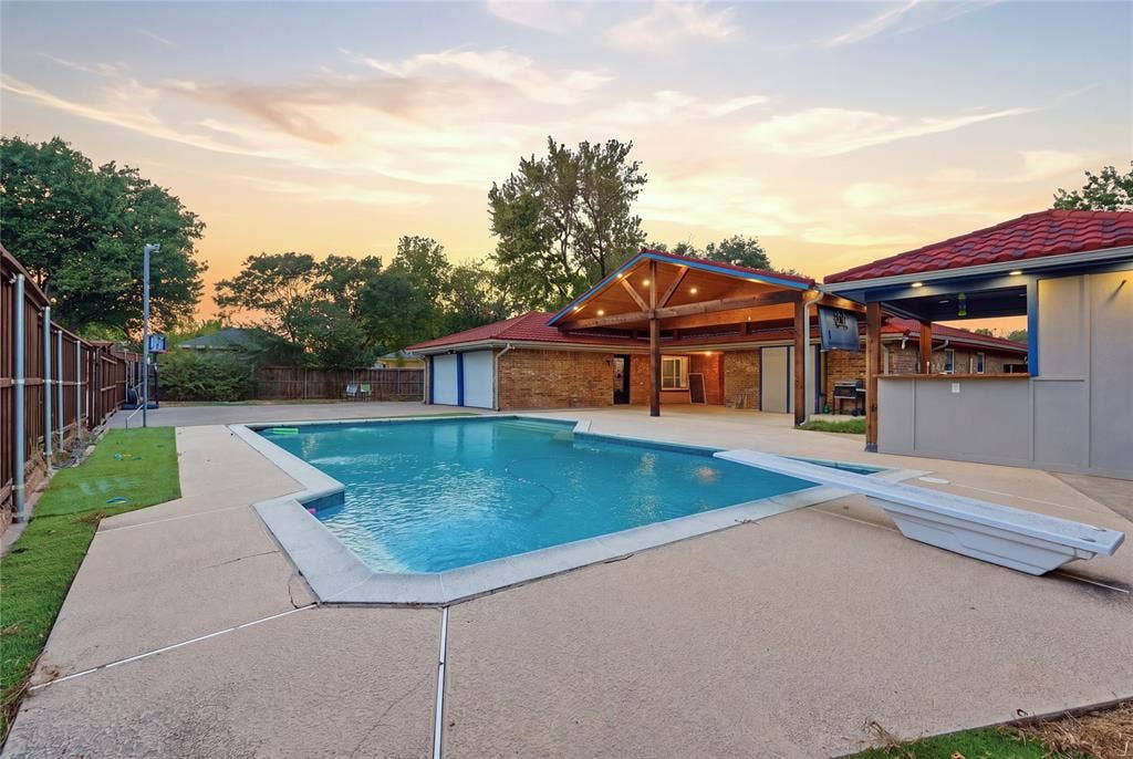 1010 Florence Drive, Duncanville, TX 75116 Expansive outdoor area featuring a swimming pool with a diving board, surrounding concrete patio, and a covered patio with exposed wood beams