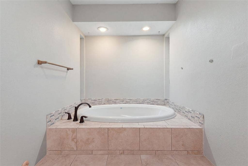 1010 Florence Drive, Duncanville, TX 75116 Recessed soaking tub with surrounding tile surround, mosaic accent tile, dark bronze-finish fixtures, and overhead recessed lighting