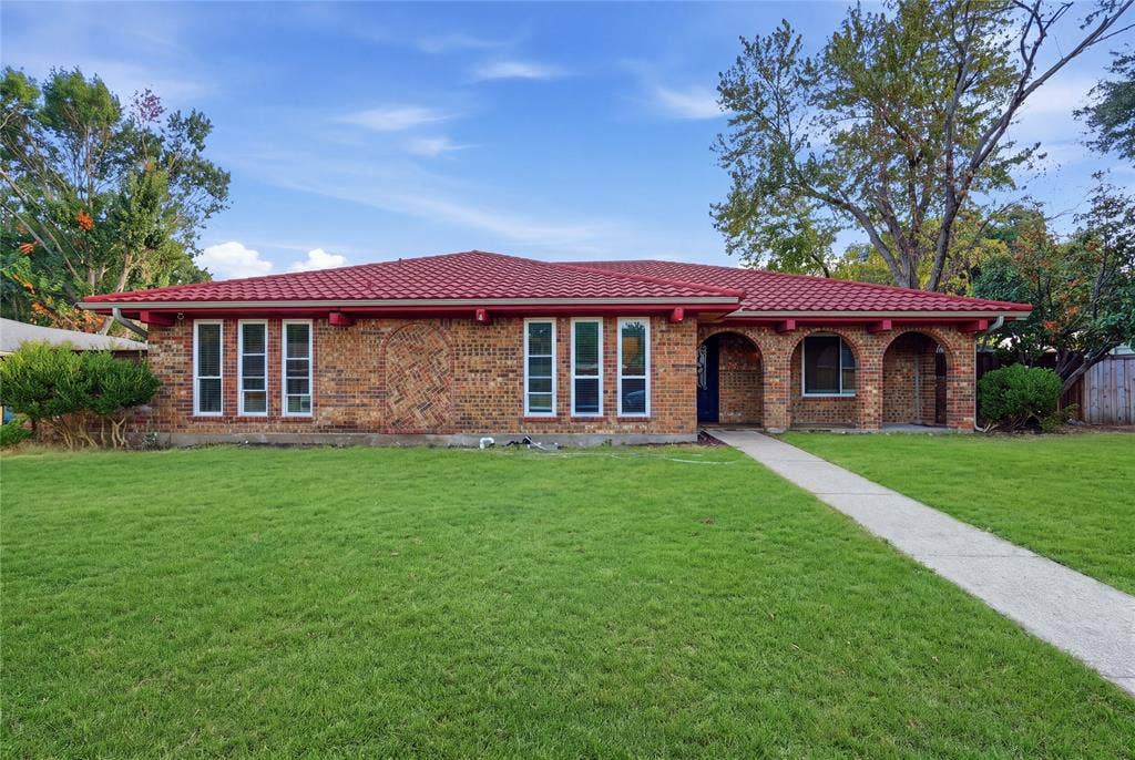 1010 Florence Drive, Duncanville, TX 75116 Brick exterior with a red tile roof, arched entryways, multiple windows, and a concrete pathway leading to the entrance