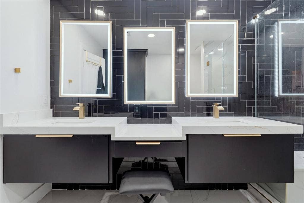 1010 Florence Drive, Duncanville, TX 75116 Dual floating vanities with integrated sinks, white countertops, black subway tile backsplash, and backlit mirrors