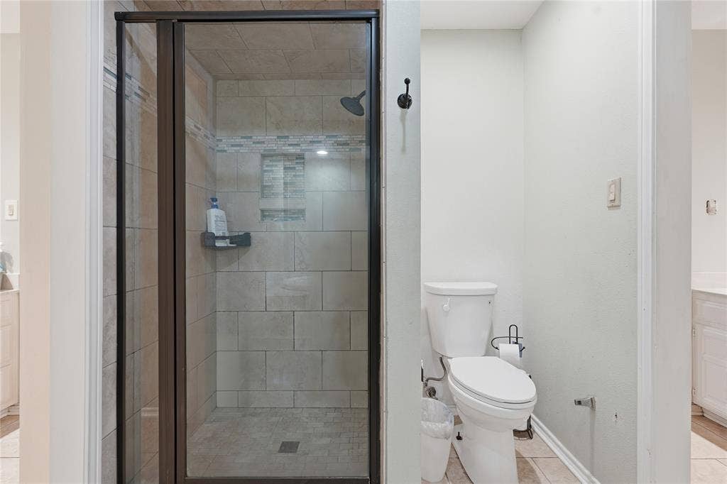 1010 Florence Drive, Duncanville, TX 75116 Glass-enclosed shower with subway tile surround, accent tile band, and built-in niche shelving