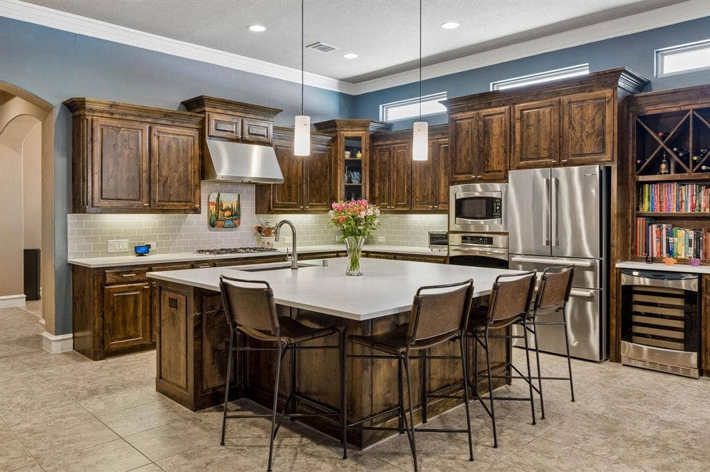 6009 Heron Bay Lane, McKinney, TX 75070 Centerpiece Island, Ground Granite sink with touchless faucet, Bosch Refrigerator, warming drawer & Wine Cooler create the perfect space for entertaining.