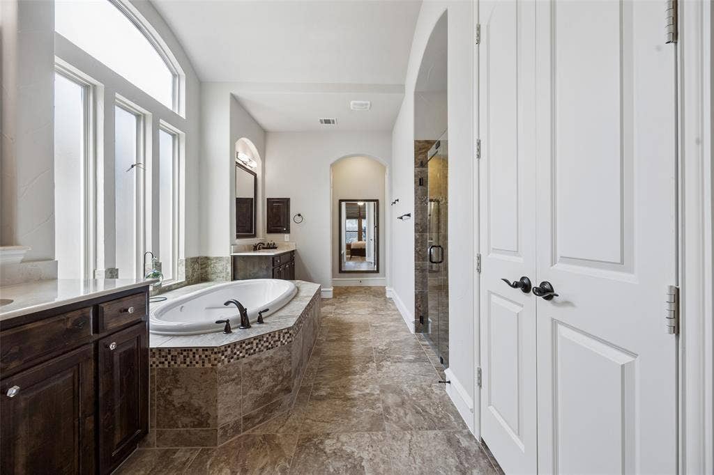 6009 Heron Bay Lane, McKinney, TX 75070 Primary bath with linen closet, built ins, jetted soaking tub, large walk in shower and a massive walk in closet.