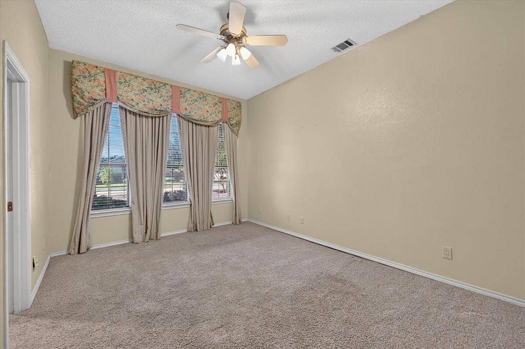 206 Harris Drive, Sunnyvale, TX 75182 Sloped ceiling room featuring a ceiling fan with integrated lighting, broad window treatments, and neutral carpeting