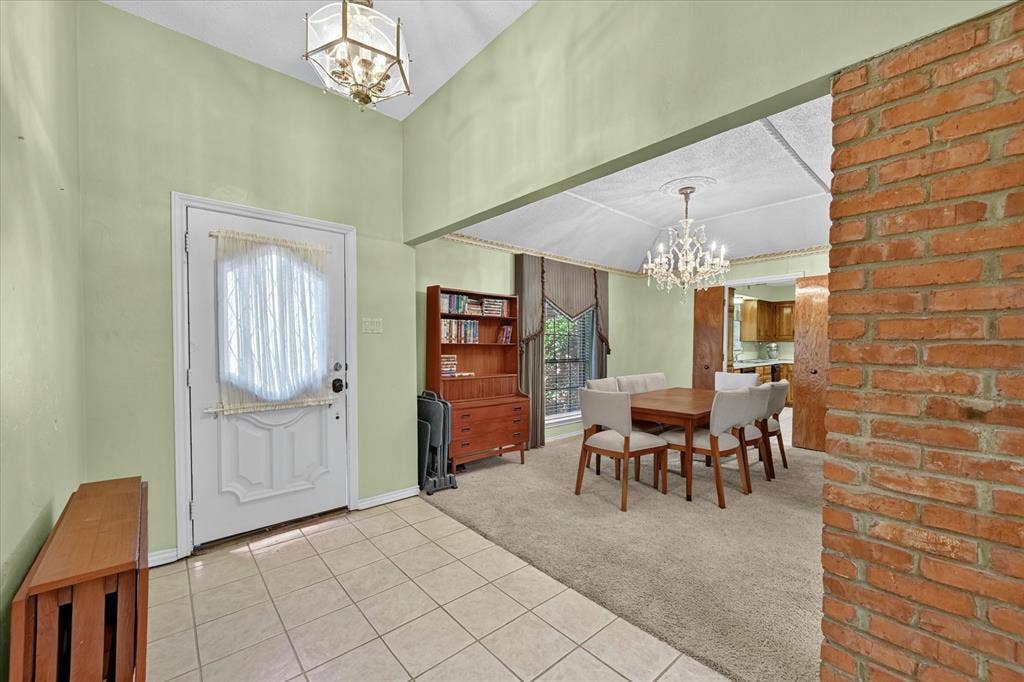 206 Harris Drive, Sunnyvale, TX 75182 Entry foyer with tile flooring and a vaulted ceiling, opening to a carpeted dining area featuring a chandelier