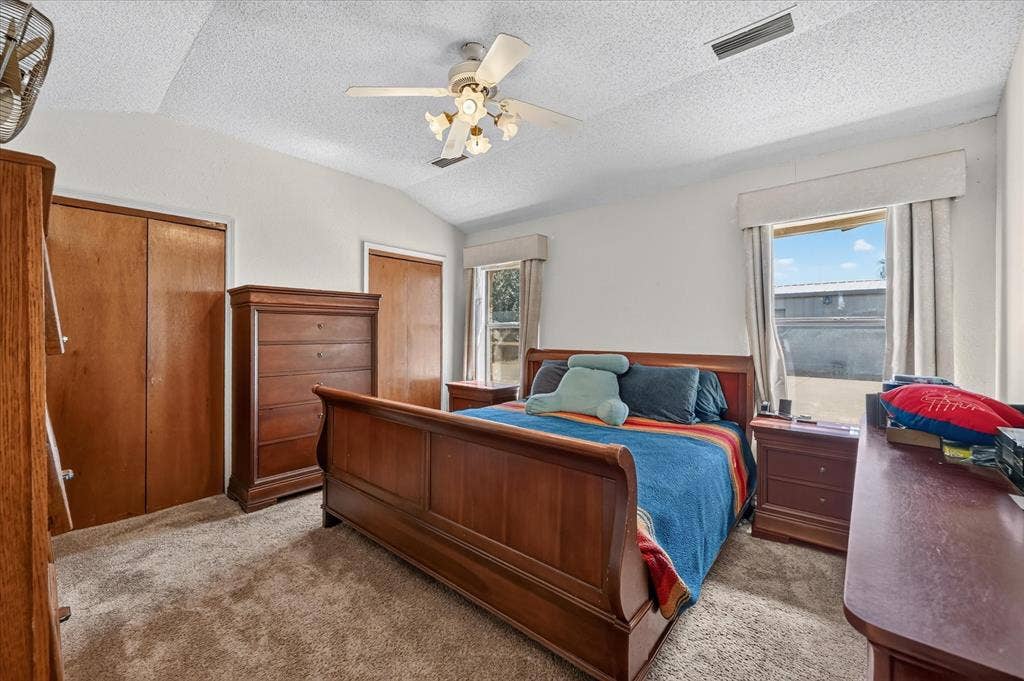 206 Harris Drive, Sunnyvale, TX 75182 Vaulted ceiling with a ceiling fan light fixture, two windows, two wood-finish bi-fold closet doors, and carpeted flooring