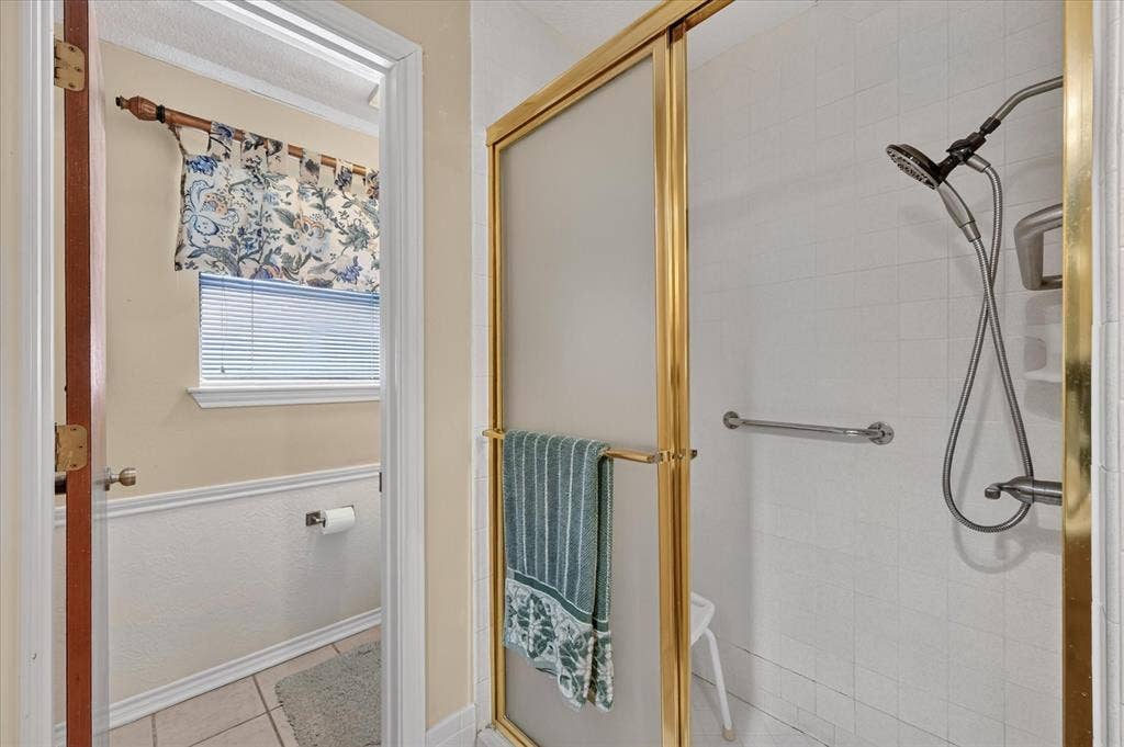 206 Harris Drive, Sunnyvale, TX 75182 Shower enclosure with gold-finish framing, white tile surround, and a handheld shower fixture