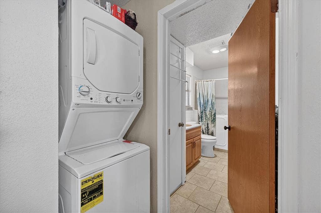 206 Harris Drive, Sunnyvale, TX 75182 Stackable washer and dryer unit, and a bathroom featuring a wood-finish vanity, white sink, and tiled flooring