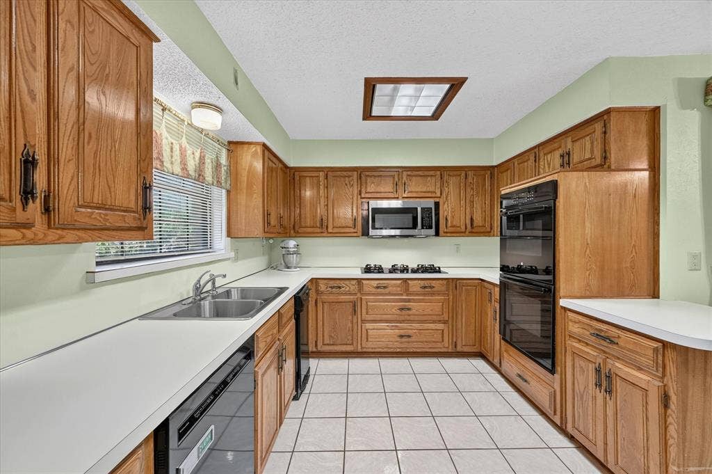 206 Harris Drive, Sunnyvale, TX 75182 U-shaped kitchen featuring wood-finish cabinetry, white countertops, a double basin stainless steel sink, a built-in double oven, and tiled flooring