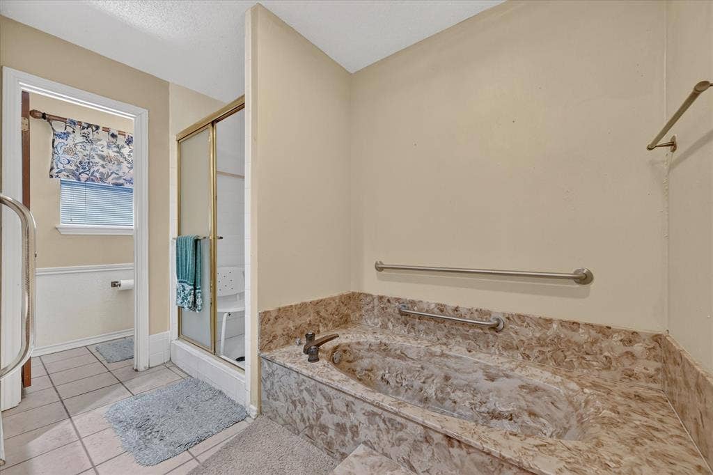 206 Harris Drive, Sunnyvale, TX 75182 Jetted soaking tub with stone surround, separate shower enclosure with sliding glass door, and tiled flooring