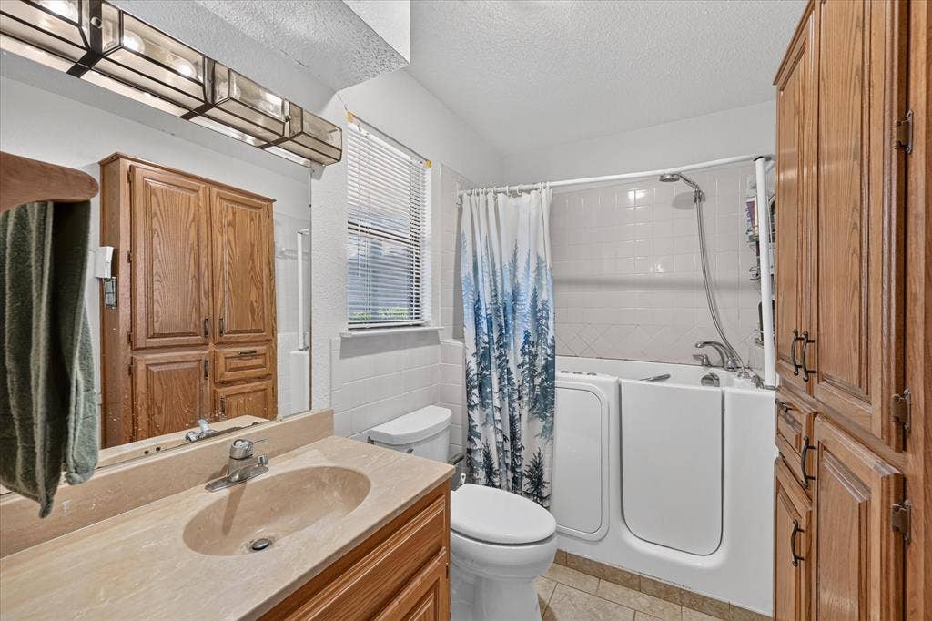 206 Harris Drive, Sunnyvale, TX 75182 Walk-in tub with shower, vanity with integrated sink, wood-finish cabinetry, and tiled flooring