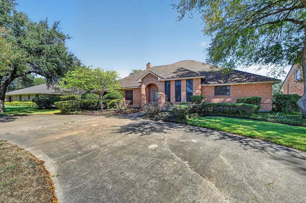 206 Harris Drive, Sunnyvale, TX 75182 Brick exterior with a gabled roof and mature trees