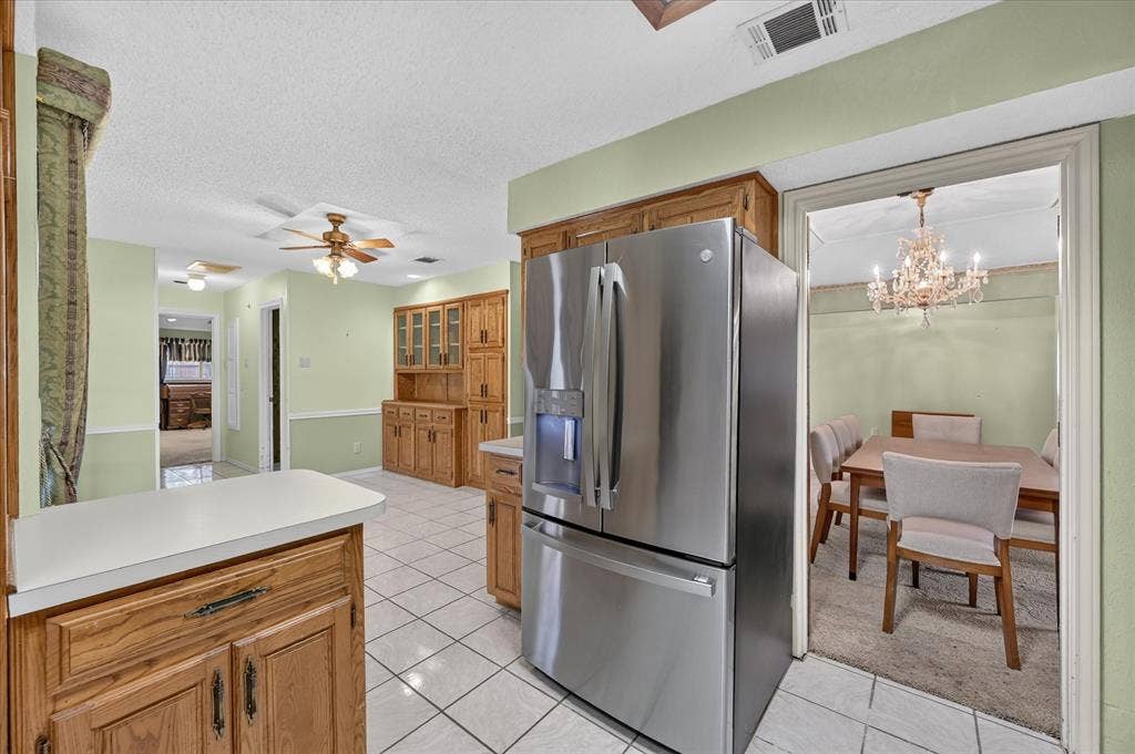 206 Harris Drive, Sunnyvale, TX 75182 Kitchen featuring tile flooring, wood cabinetry, a built-in hutch with glass-front uppers, a stainless steel refrigerator, and ceiling fans
