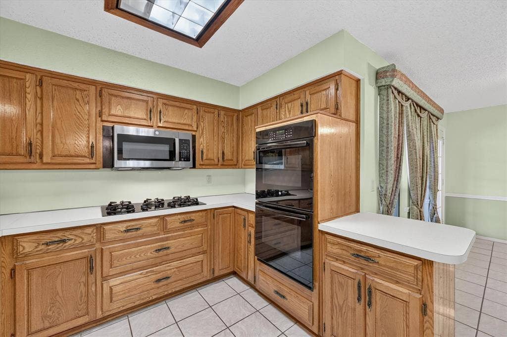 206 Harris Drive, Sunnyvale, TX 75182 Kitchen featuring wood cabinetry, white countertops, built-in stainless steel microwave, gas cooktop, and tile flooring