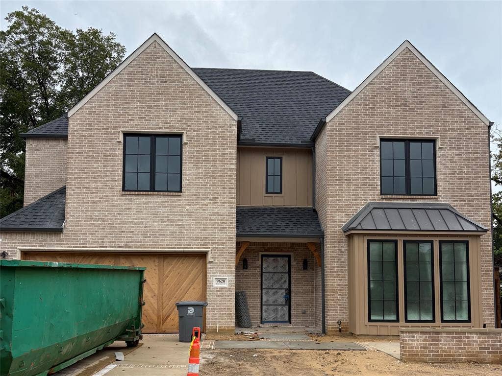 9620 Lakemont Drive, Dallas, TX 75220 Light-toned brick exterior with dark-framed windows, a prominent bay window with a metal roof, and a wood-panel garage door
