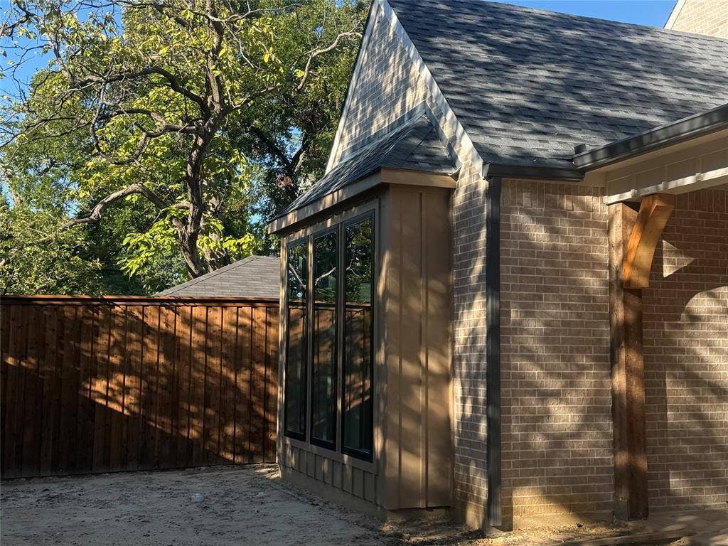 9620 Lakemont Drive, Dallas, TX 75220 Tan brick exterior, wood siding, dark framed windows, wood beam accent, and a privacy fence