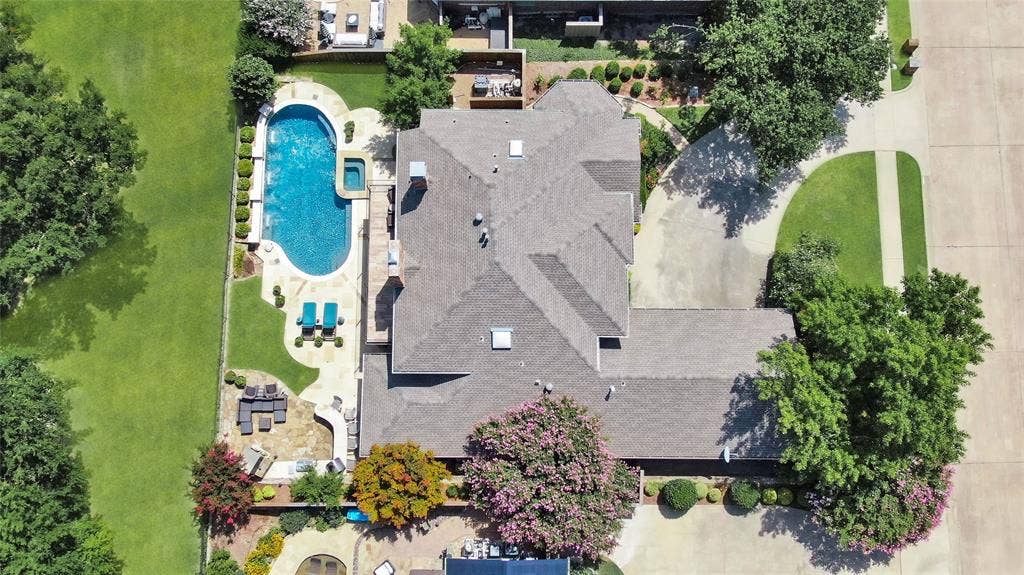 1204 Hills Creek Drive, McKinney, TX 75072 Expansive outdoor living area featuring a large swimming pool, integrated spa, paved patio, and mature trees