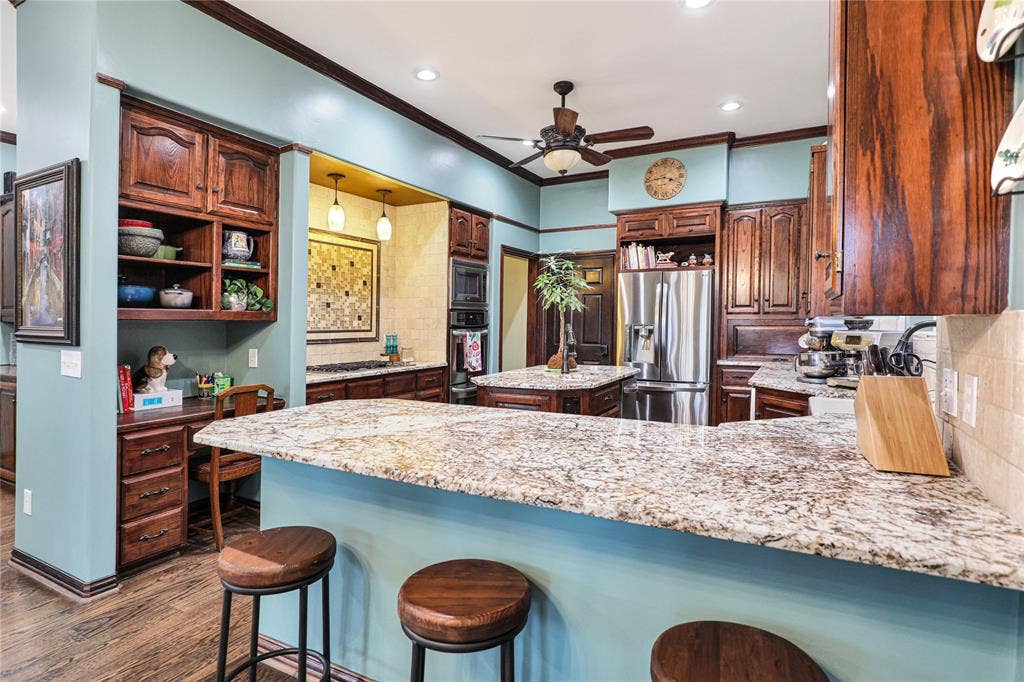 1204 Hills Creek Drive, McKinney, TX 75072 Granite countertops, extensive wood cabinetry, stainless steel appliances, wood-finish flooring, and recessed lighting