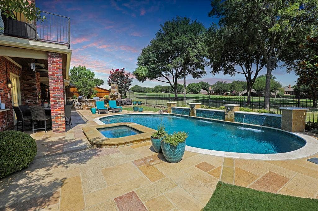 1204 Hills Creek Drive, McKinney, TX 75072 Expansive outdoor living area featuring a freeform pool with integrated spa, waterfall features, and a spacious paver patio