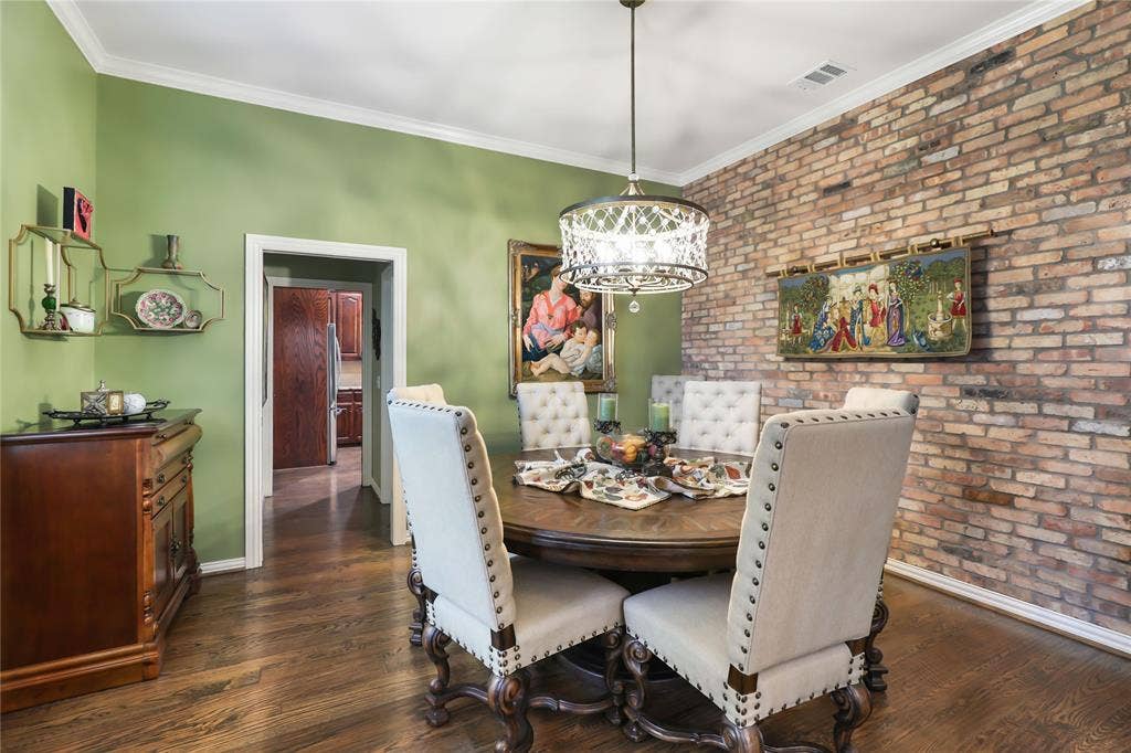 1204 Hills Creek Drive, McKinney, TX 75072 Exposed brick accent wall, wood-finish flooring, white crown molding, and a decorative chandelier