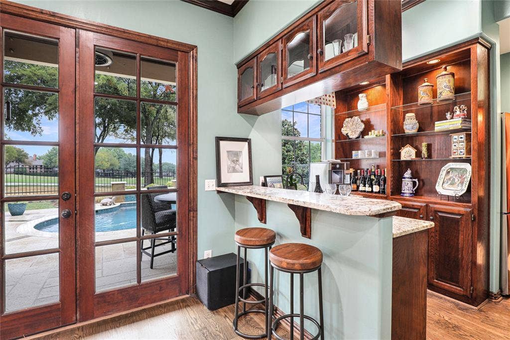 1204 Hills Creek Drive, McKinney, TX 75072 Built-in wet bar with a granite countertop, upper and lower wood cabinetry, and an integrated wine rack