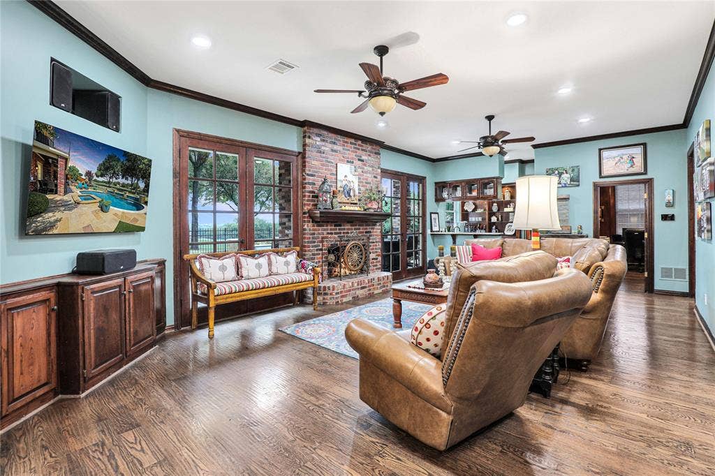 1204 Hills Creek Drive, McKinney, TX 75072 Hardwood flooring, brick-surround fireplace, built-in cabinetry, French doors, and ceiling fans