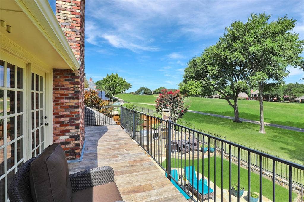 1204 Hills Creek Drive, McKinney, TX 75072 Brick exterior featuring a private balcony with wood-finish flooring, black metal railing, and expansive green spaces