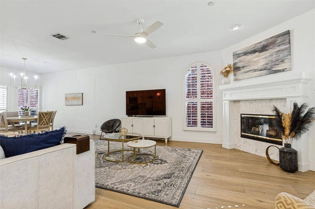 6816 Livorno Lane, Frisco, TX 75034 Light colored Luxury vinyl plank flooring throughout, a gas fireplace with a tiled surround, a costume wood decorative mantel, and an arched window with plantation shutters