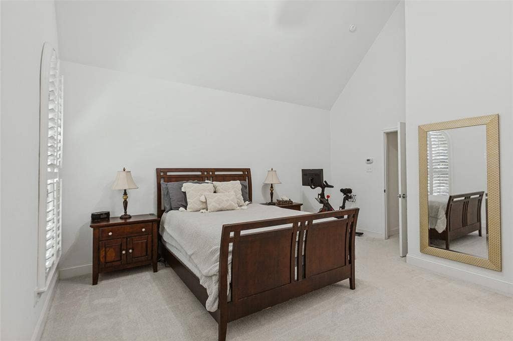 6816 Livorno Lane, Frisco, TX 75034 Primary bedroom with ensuite, Vaulted ceiling with a ceiling fan, white plantation shutters, and light-toned carpeting