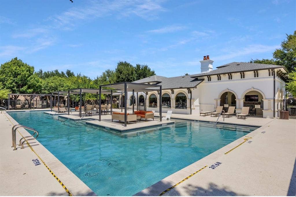 6816 Livorno Lane, Frisco, TX 75034 Expansive swimming pool with integrated tanning ledges, multiple shade pergolas, and a stucco-finished building featuring arched openings and a dark tile roof
