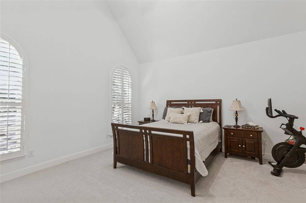 6816 Livorno Lane, Frisco, TX 75034 Primary Suite featuring Vaulted ceiling, arched windows with plantation shutters, light-toned carpeting, and white wall finishes