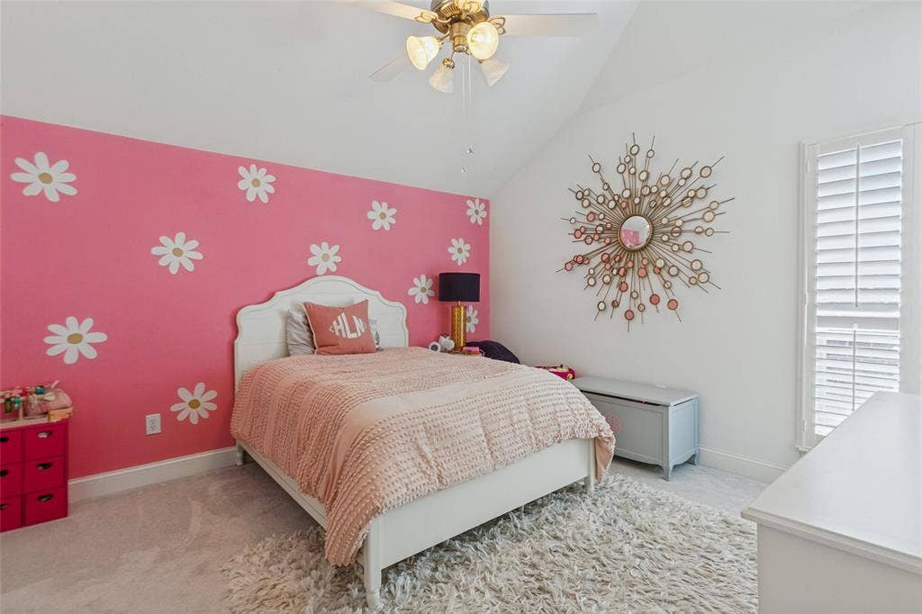 6816 Livorno Lane, Frisco, TX 75034 Secondary bedroom with Vaulted ceiling, white plantation shutters, ceiling fan with integrated lighting, and pink accent wall