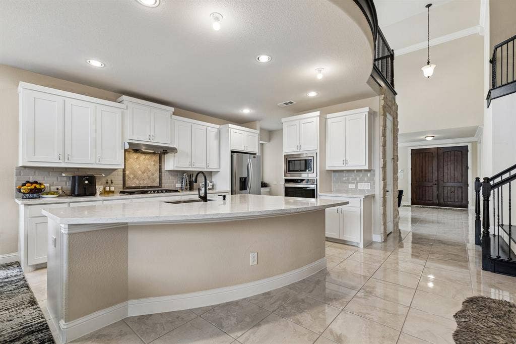 3613 Sparkling Drive, Plano, TX 75074 Kitchen featuring white cabinetry, a large kitchen island with a sink, stainless steel appliances, and a tiled backsplash