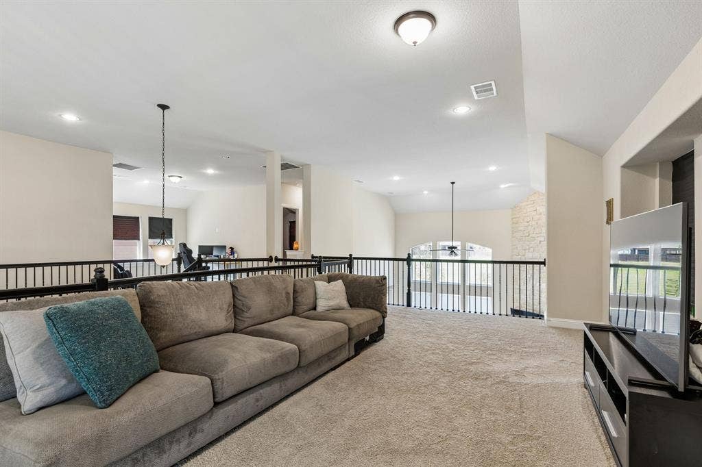 3613 Sparkling Drive, Plano, TX 75074 Spacious carpeted loft with black metal railings, recessed lighting, and a neutral color palette