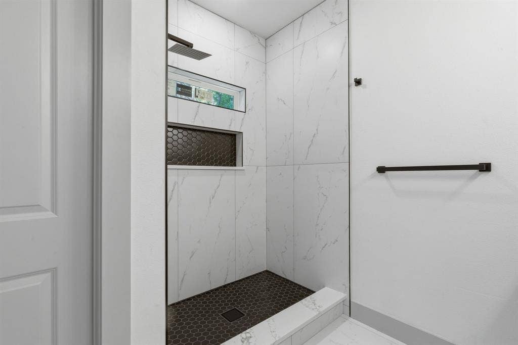 14583 Cherokee Lane, Log Cabin, TX 75148 Shower with white marble-look tile, dark hexagonal floor tile, dual built-in shower niches, and a rainfall showerhead